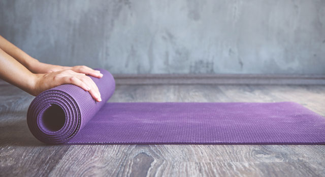 woman rolling up a yoga mat